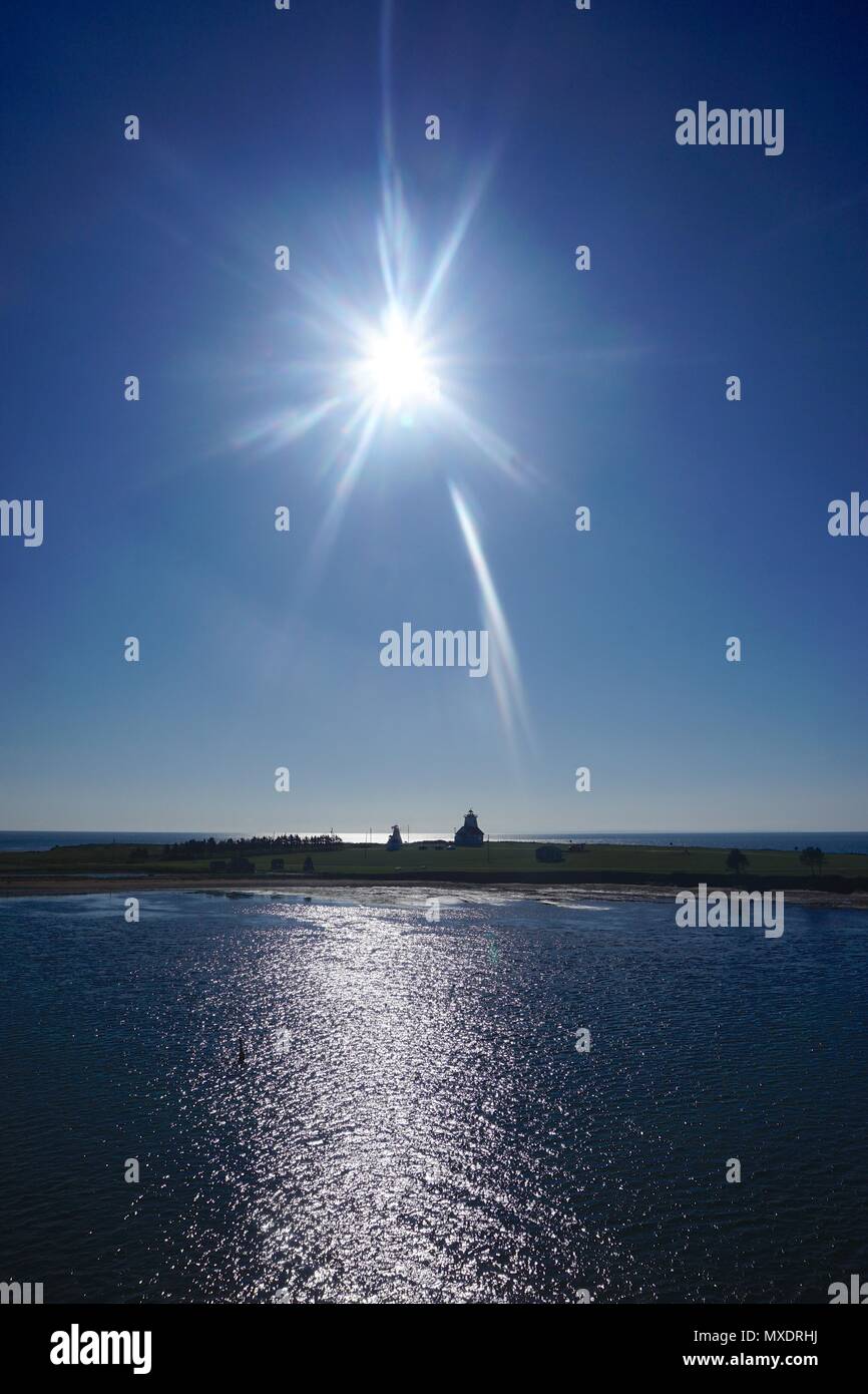 Eine sternförmige Sun flare über der Silhouette des Holzes Inseln Leuchtturm (1876) an der südöstlichen Küste von Prince Edward Island, Kanada. Stockfoto