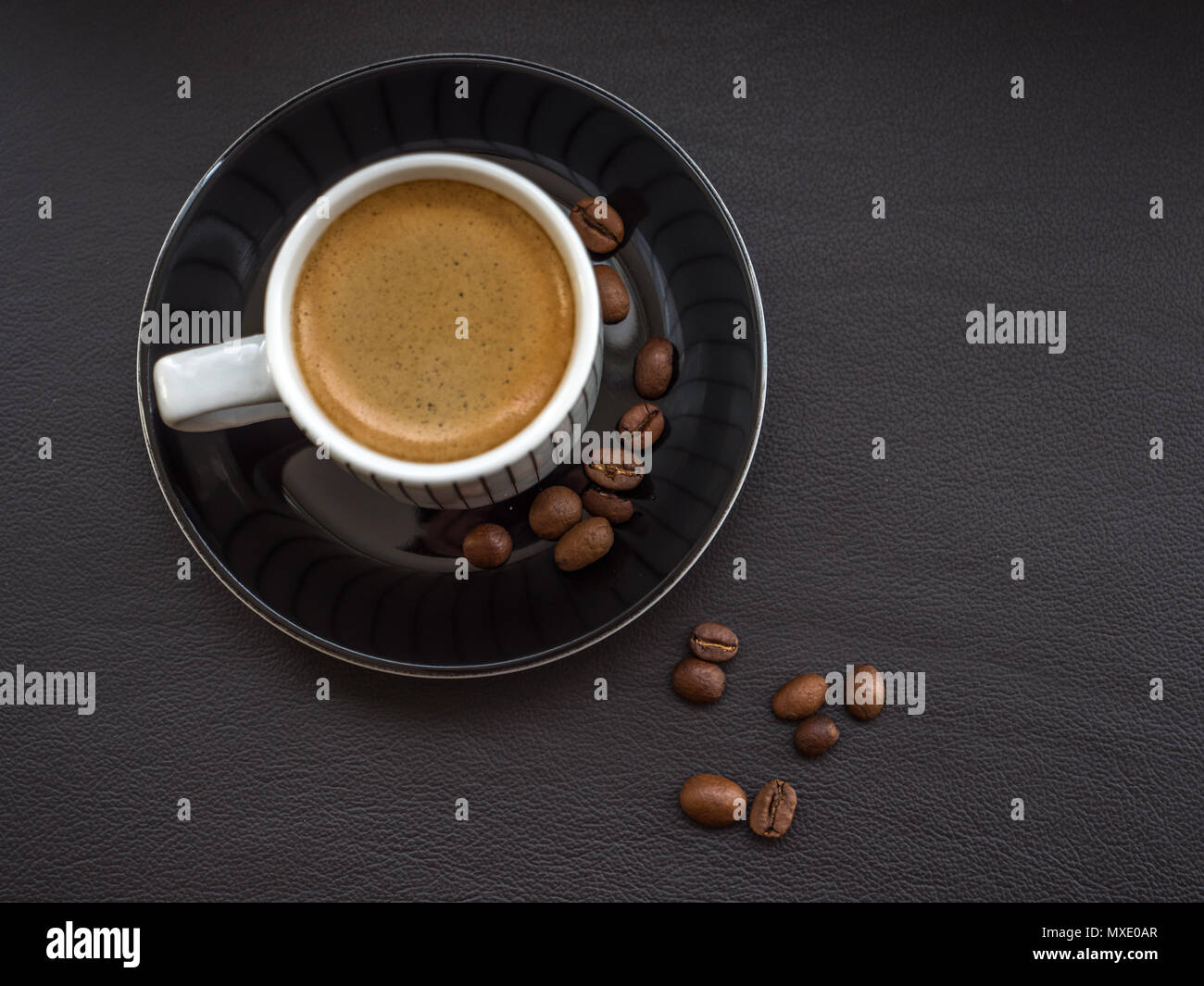 Kaffee auf dunklem Leder Oberfläche mit Kaffeebohnen Stockfoto
