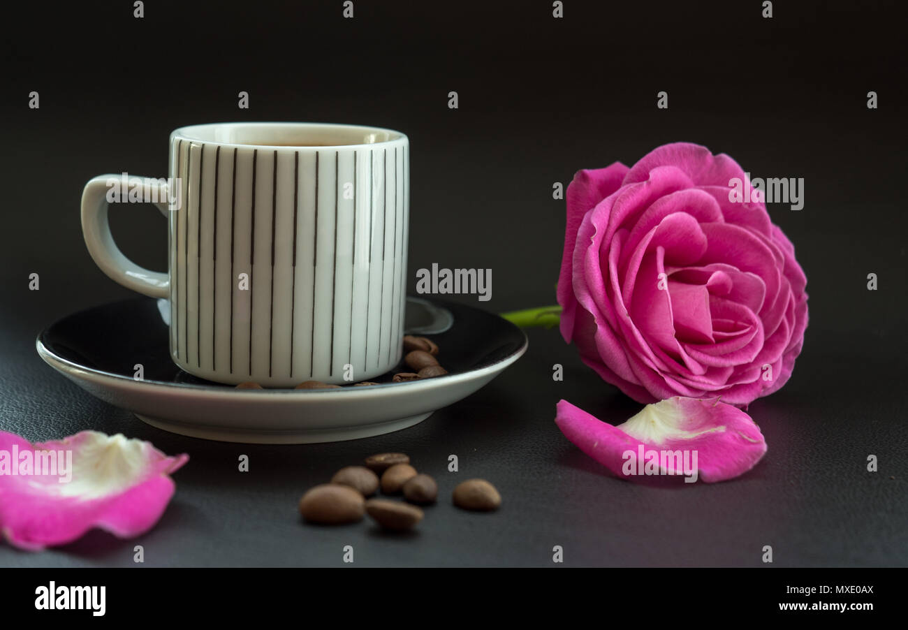 Kaffee mit rosa Rose auf dunklem Leder Oberfläche mit Kaffeebohnen Stockfoto