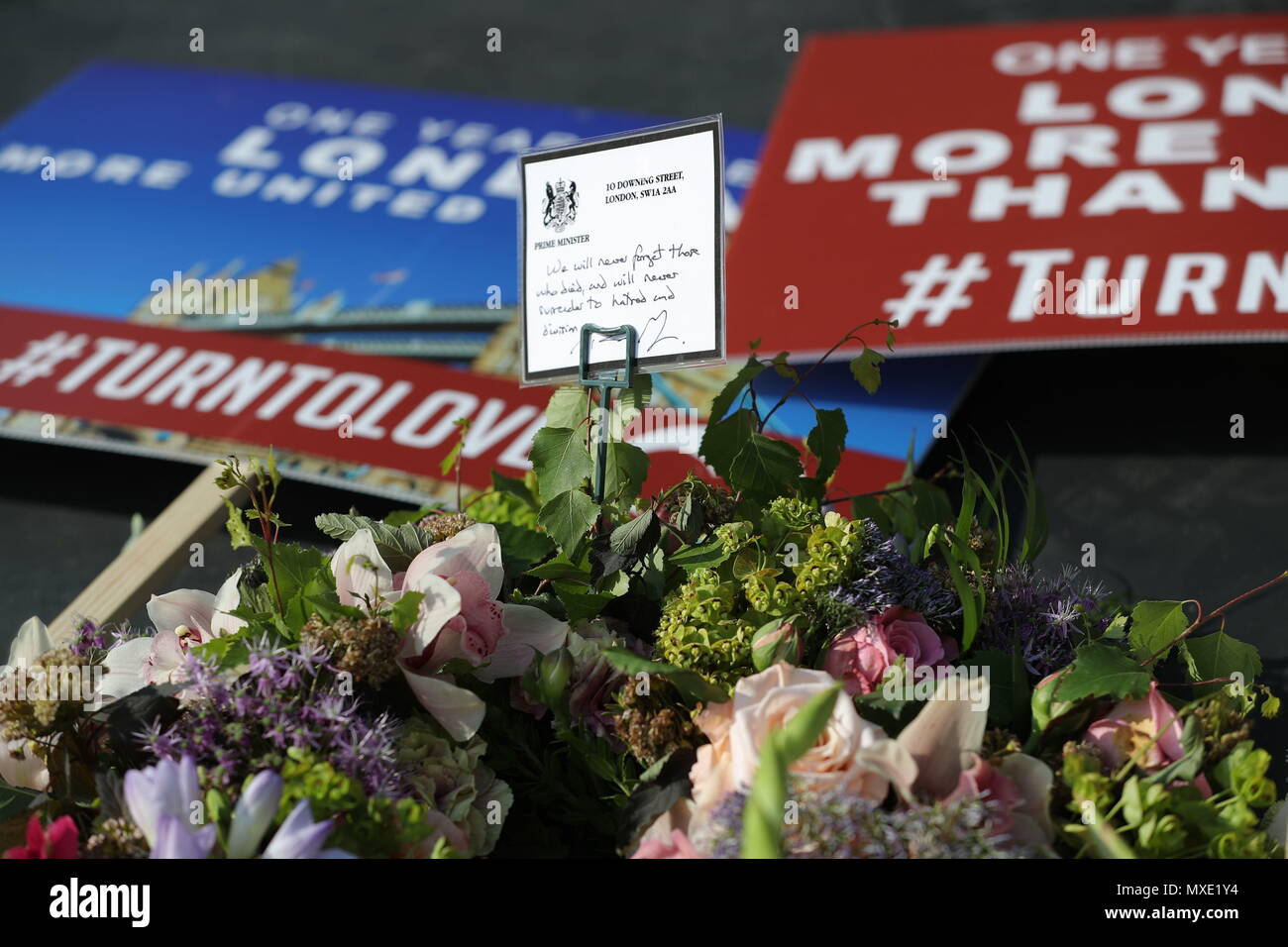 Ein Hinweis auf der linken Seite entlang einem floralen Tribut von Premierminister Theresa kann auf die London Bridge, während Veranstaltungen zu einem Jahr Mark seit dem Terroranschlag auf die London Bridge und Borough. Stockfoto