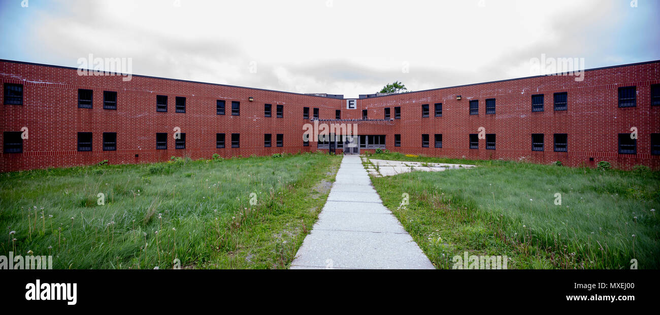 Von außen Backstein cellblock mit bewachsenen Hof in verlassenen Gefängnis. Stockfoto