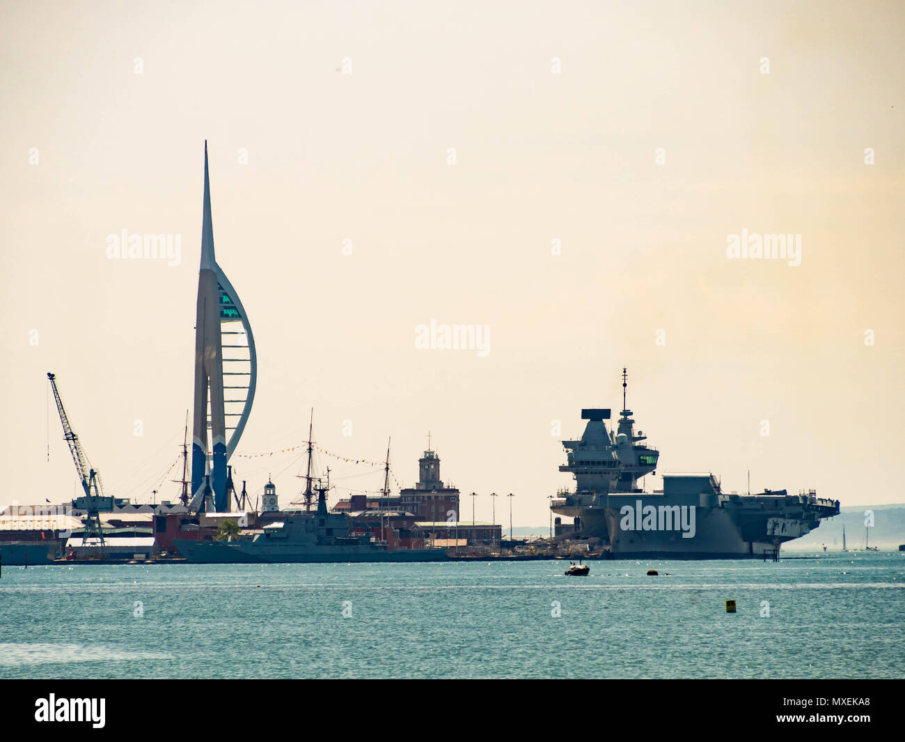 Der Flugzeugträger HMS Queen Elizabeth, liegt neben Portsmouth Dockyard mit dem Spinnaker Tower im Hintergrund Stockfoto
