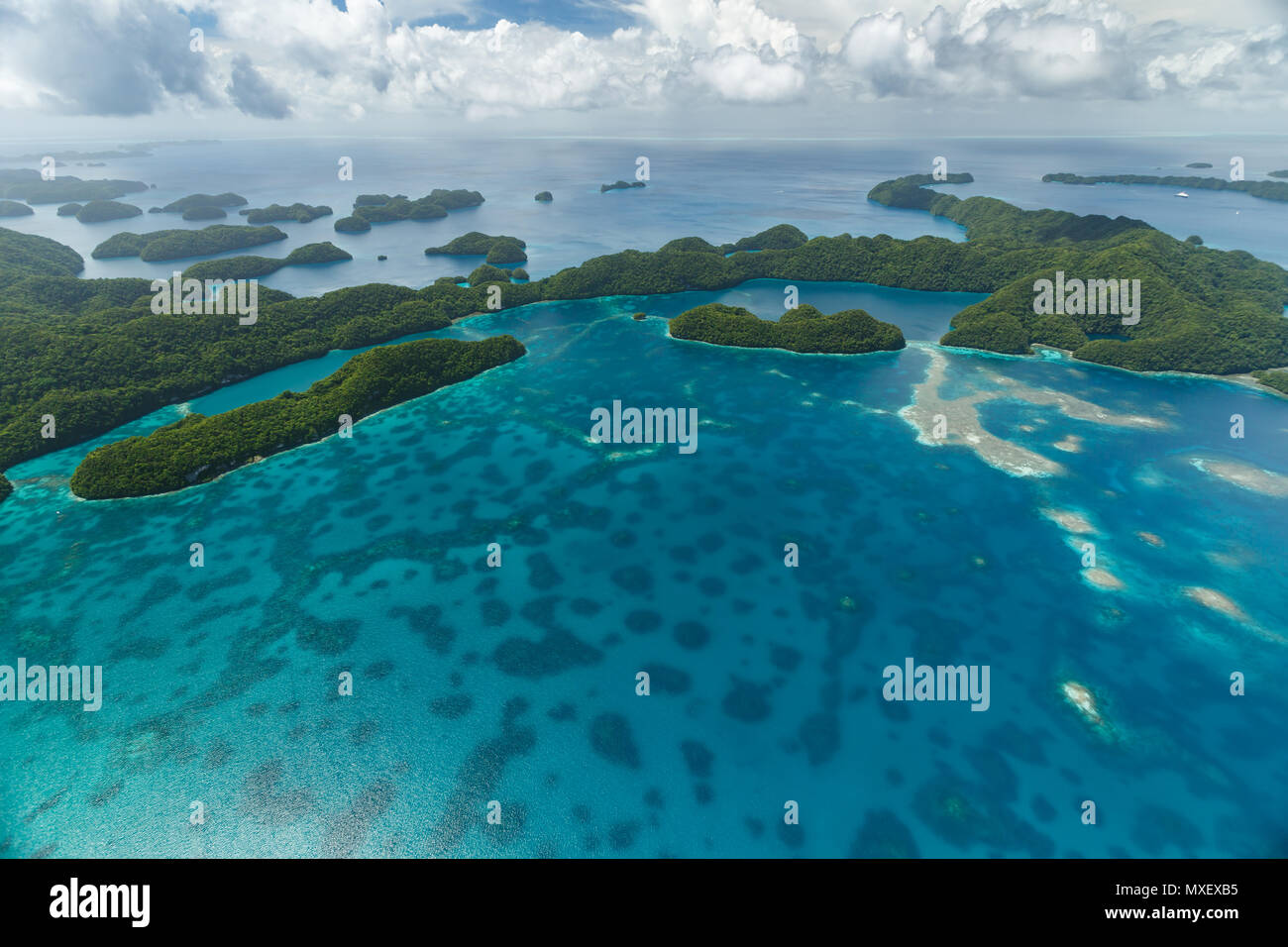 Luftaufnahme von neugierig mustern der Korallenriffe, coral Atolle und Inseln, die durch das türkisfarbene Wasser der Südsee mit Sammeln von Wolke umgeben Stockfoto