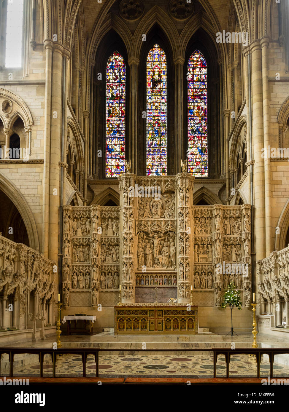 Altar und kunstvoll geschnitzten Retabel unterhalb der Glasfenster der Viktorianischen Kathedrale von Truro, Cornwall, Großbritannien Stockfoto