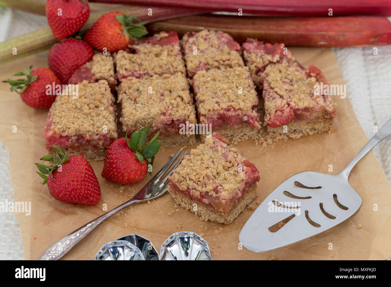 Lecker und gesund Sommer Snack oder Dessert. Hausgemachte glutenfreie Rhabarber und Erdbeeren bröckeln Slice, mit frischem Obst. Stockfoto