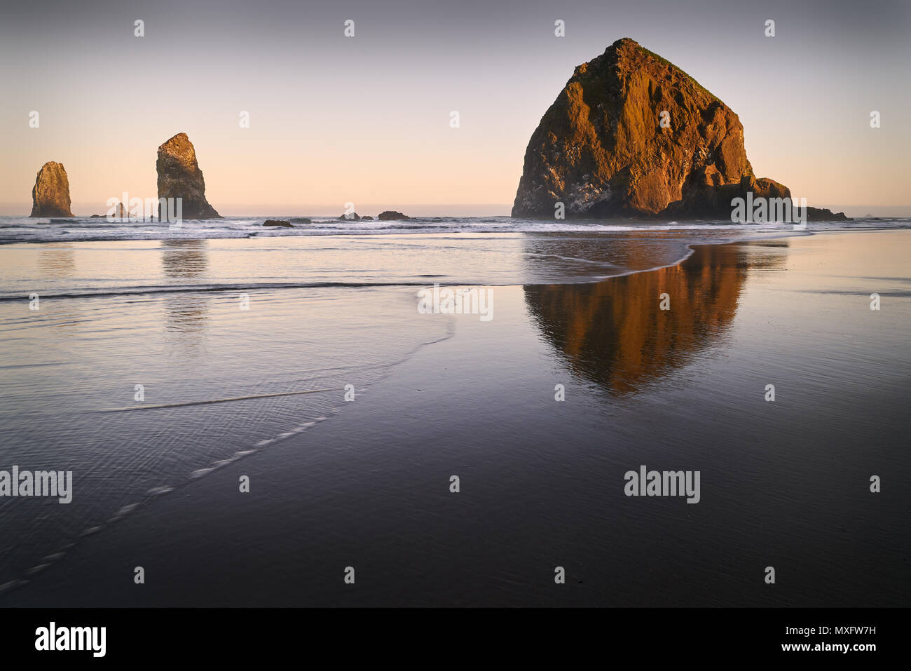 Haystack Rock Sunrise, Cannon Beach, California Sunrise At Haystack Rock in Cannon Beach, Oregon, wie die Wellen auf den Strand wäscht. In den Vereinigten Staaten. Stockfoto
