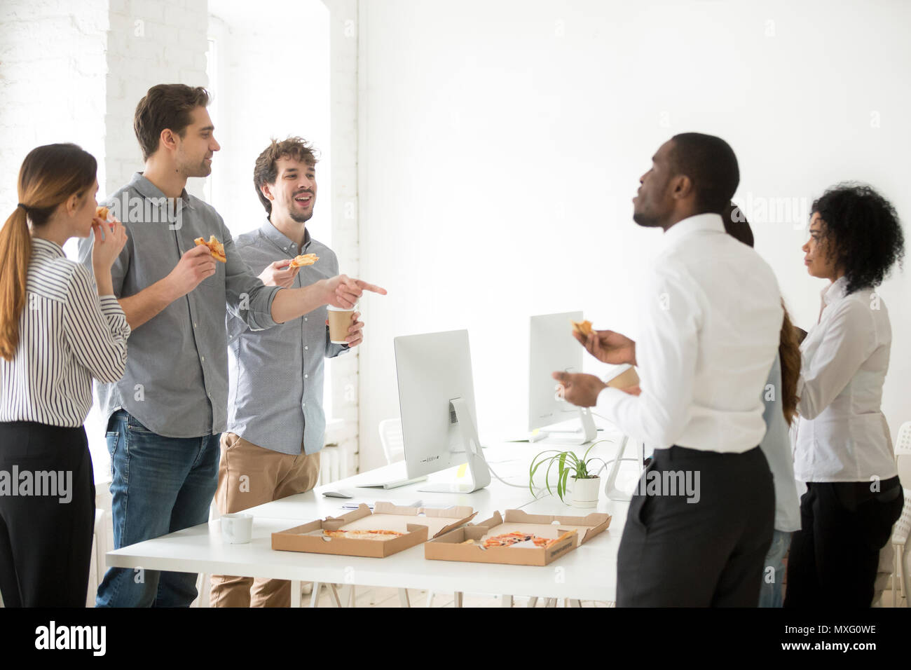 Positive Team essen Pizza und Chatten am Arbeitsplatz Stockfoto