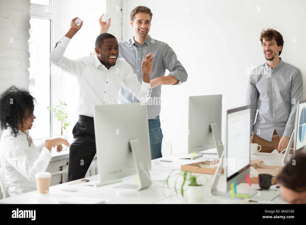 Positive gemischtrassiges Team Spaß werfen Papier Kugeln Stockfoto