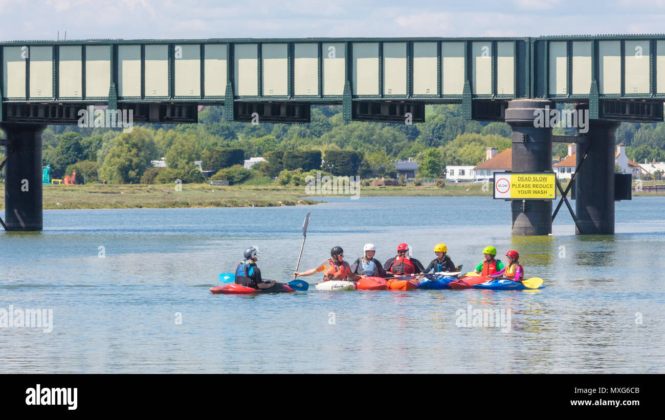 Shoreham-By-Sea, Großbritannien; 3. Juni 2018; eine Gruppe von Kanuten mit bunten Kleidung, Helme und Boote auf dem Fluss Adur mit Brücke hinter Stockfoto