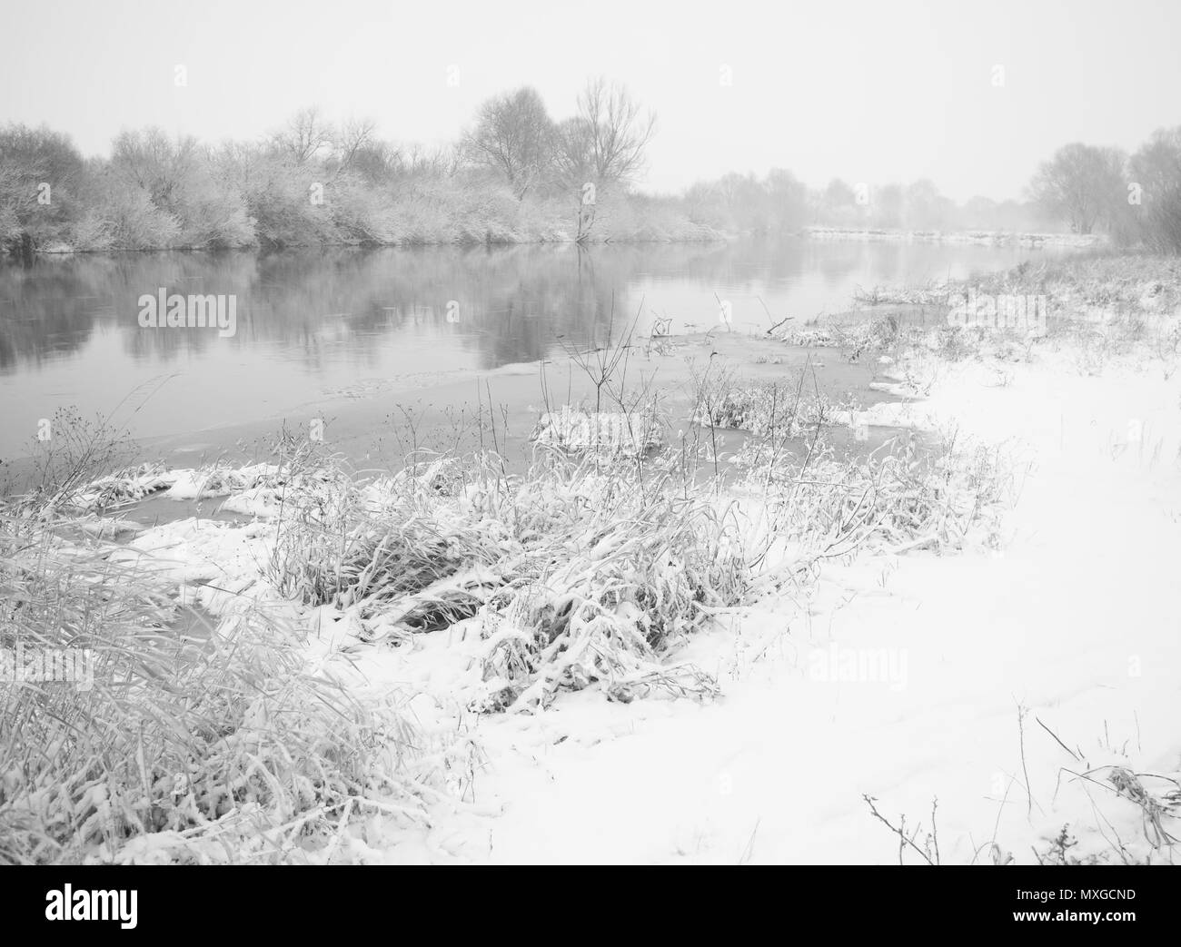 Schneefall auf einem ruhigen Fluss im winter Stockfoto