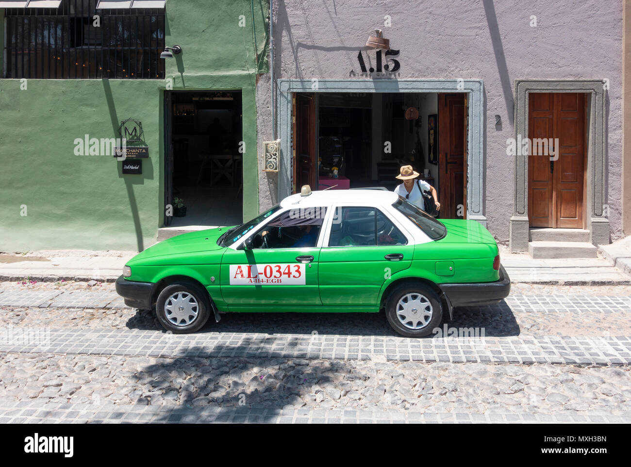 Ein grünes Taxi Abholung eine Frau Passagier in San Miguel de Allende Stockfoto