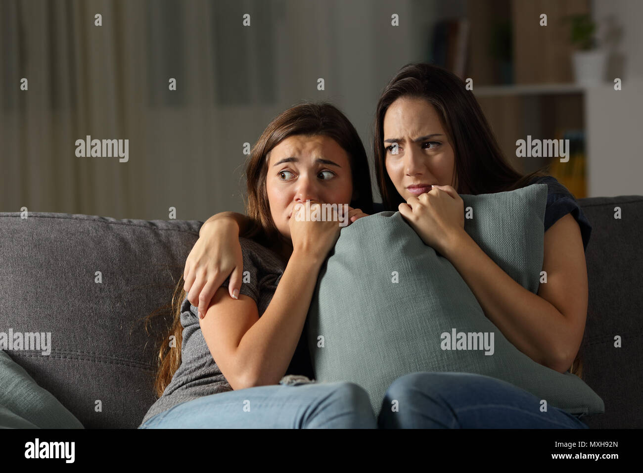 Angst Freunde hören Geräusche in der Nacht auf einer Couch im Wohnzimmer zu Hause sitzen Stockfoto