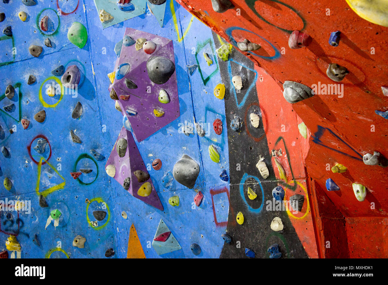 Eine Kletterwand einer Kletterhalle mit verschiedenen Farben und Formen Felsen und Griffe. Stockfoto