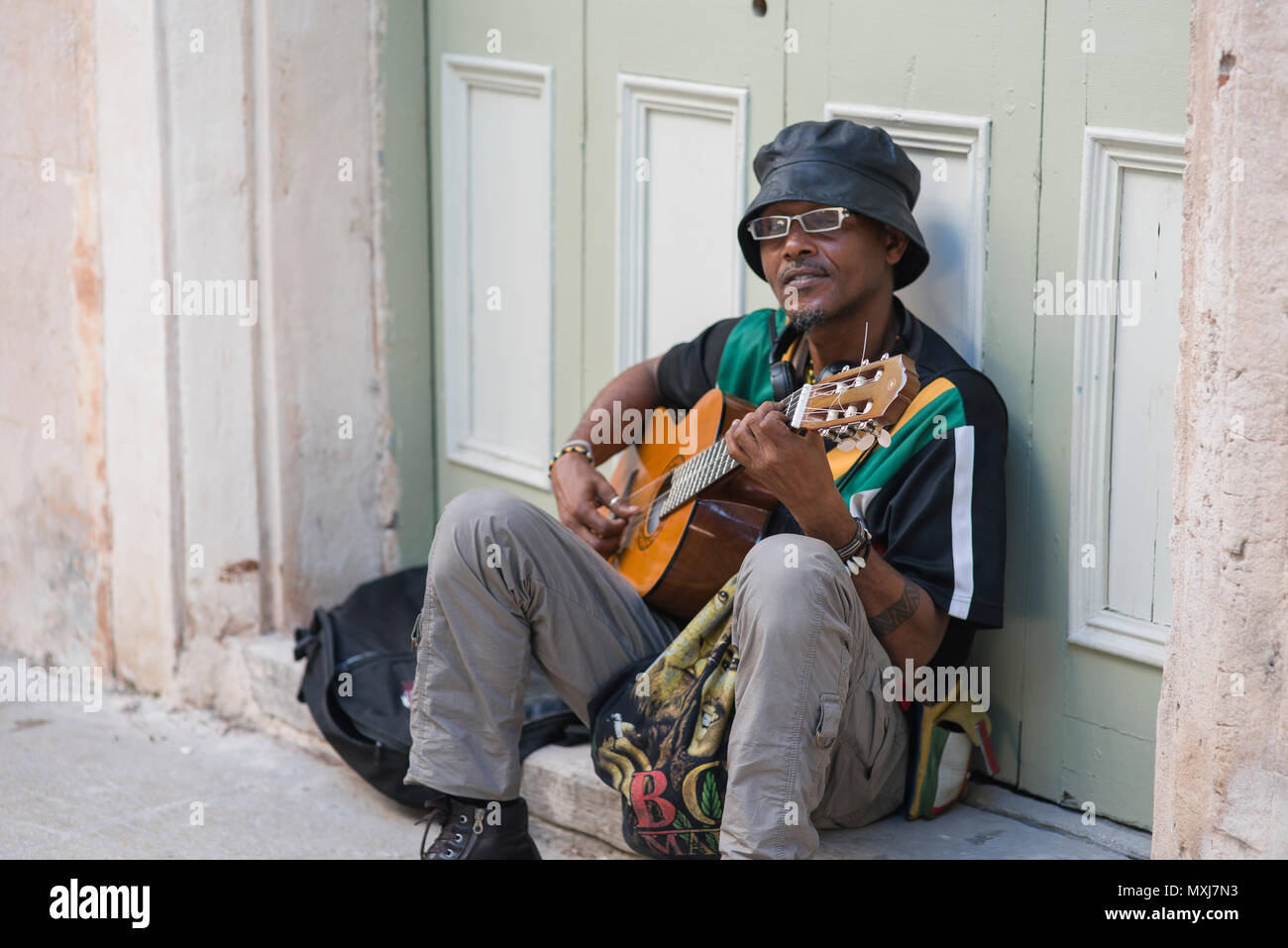 Ein freundlicher Mann spielt Gitarre auf einem Stoop in Havanna, Kuba. Stockfoto