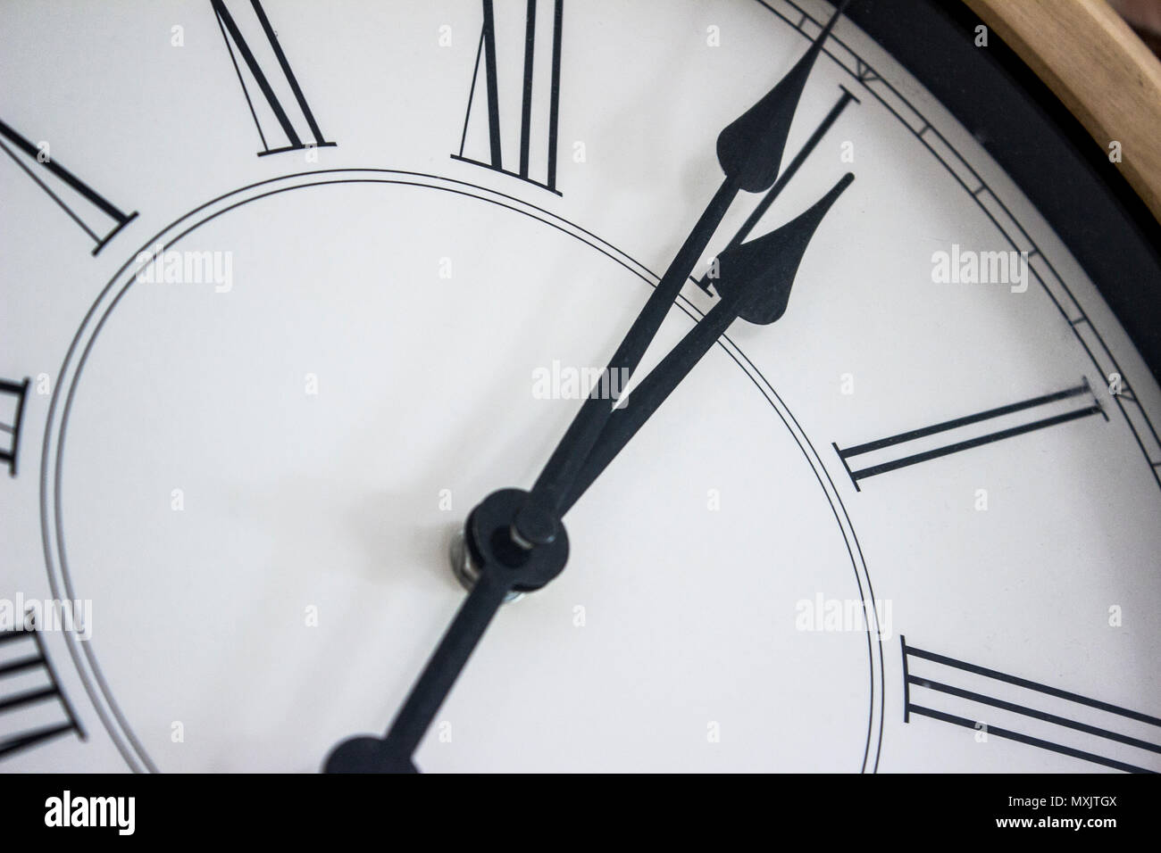 Nahaufnahme der Hände eines hölzernen Wanduhr mit römischen Ziffern. Stockfoto