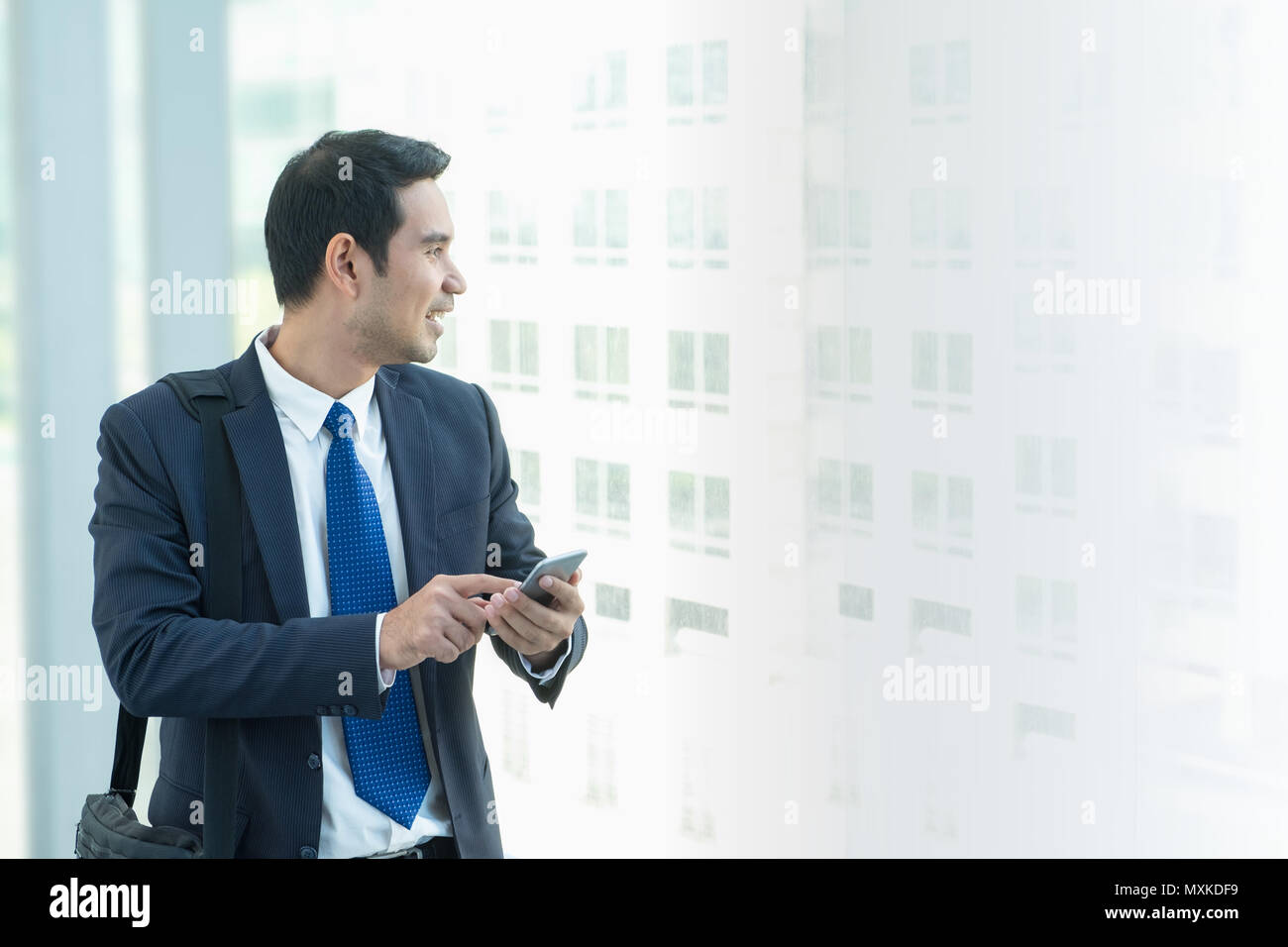 Business Mann zu Fuß und mit Handy zu chatten mit Freunden nach der Arbeit im Korridor Bürogebäude Stockfoto