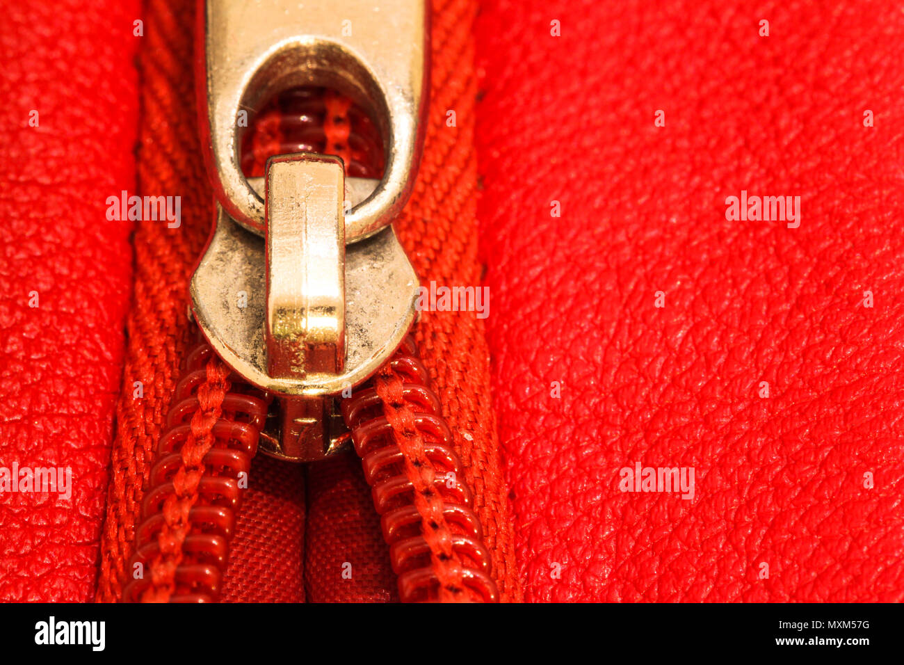 Reißverschluss teilweise offenen verbindlich zusammen zwei Schichten aus rotem Stoff Textil- und rot leder unter hoher Vergrößerung schließen Detail. Stockfoto