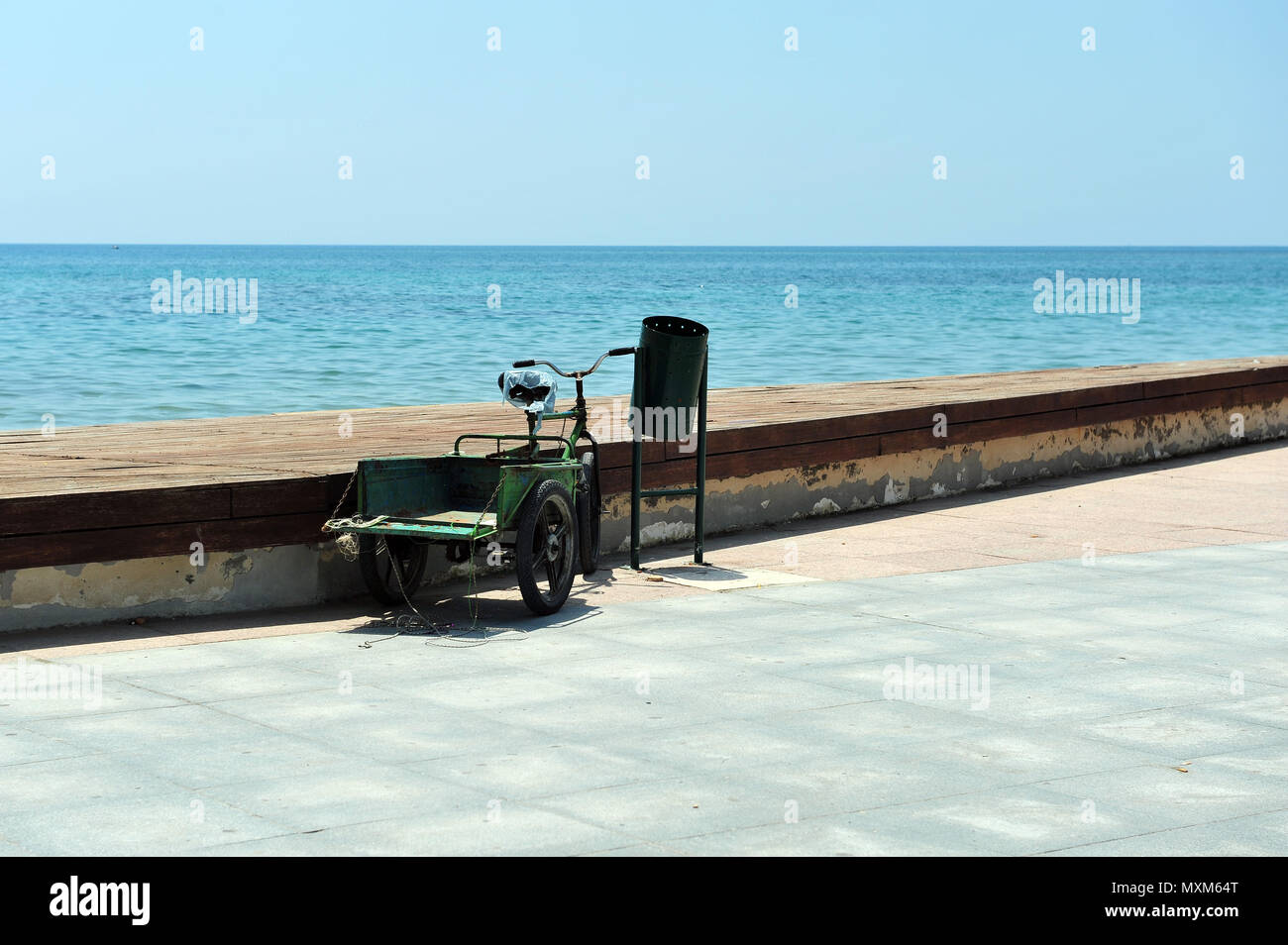 Grün Dreirad für Erwachsene neben dem grünen Müll geparkt kann durch den Hafen. Fahrrad mit Gepäckträger. Stockfoto