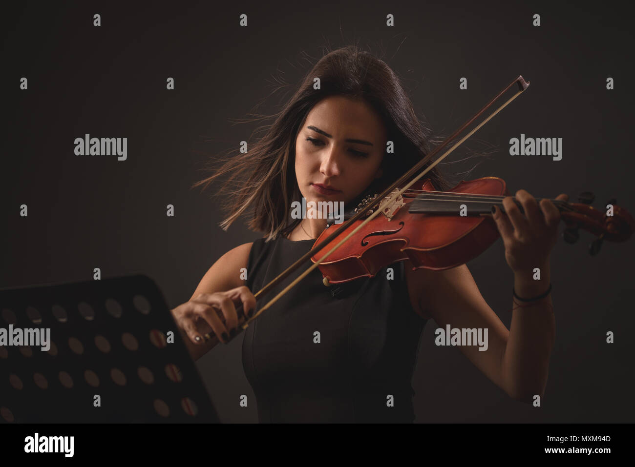 Hübsche junge Frau spielt eine Violine über schwarzen Hintergrund. Stockfoto
