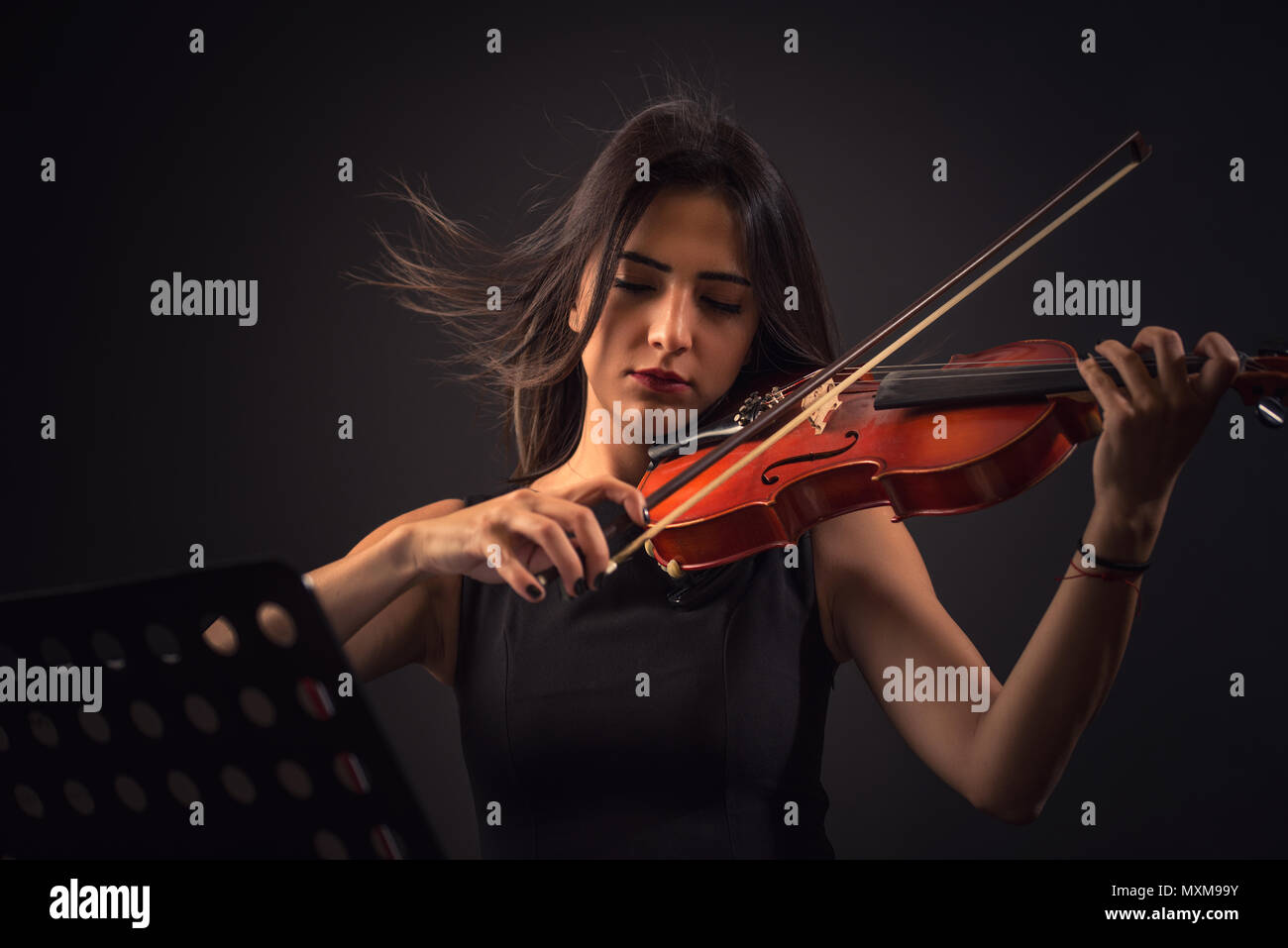Hübsche junge Frau spielt eine Violine über schwarzen Hintergrund. Stockfoto
