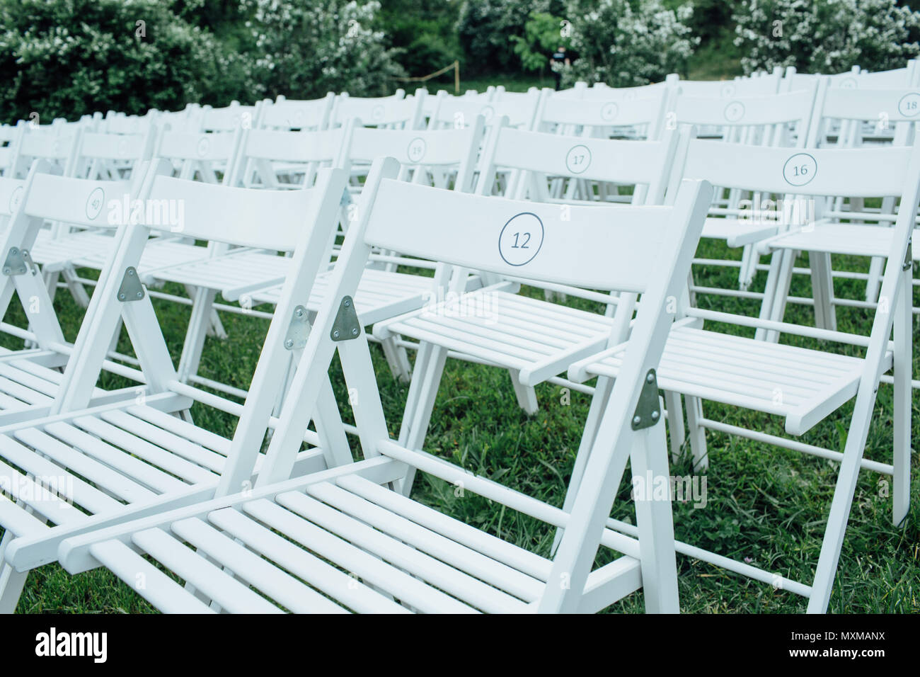 Stühle durch den grünen Rasen in der Vorbereitung für eine Hochzeit Stockfoto