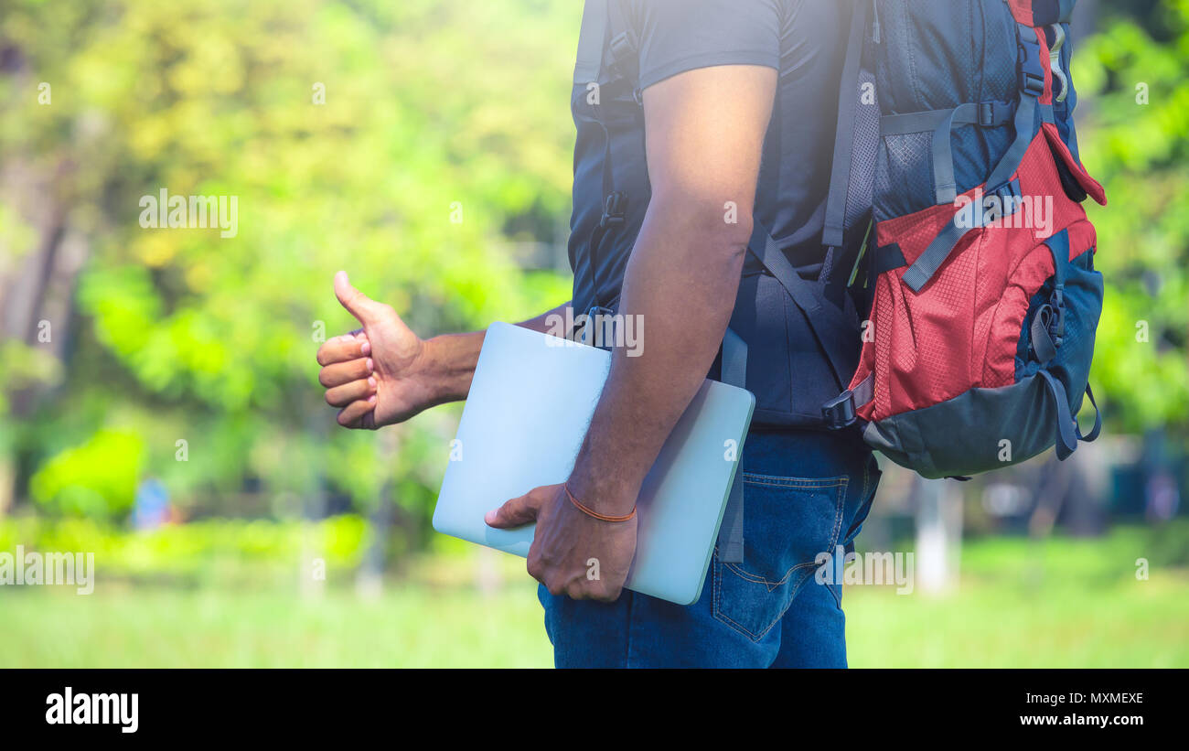 Mann mit einem Rucksack in einem Park während der Tag. Backpacker Holding einen Laptop. Digital nomad Konzept Stockfoto