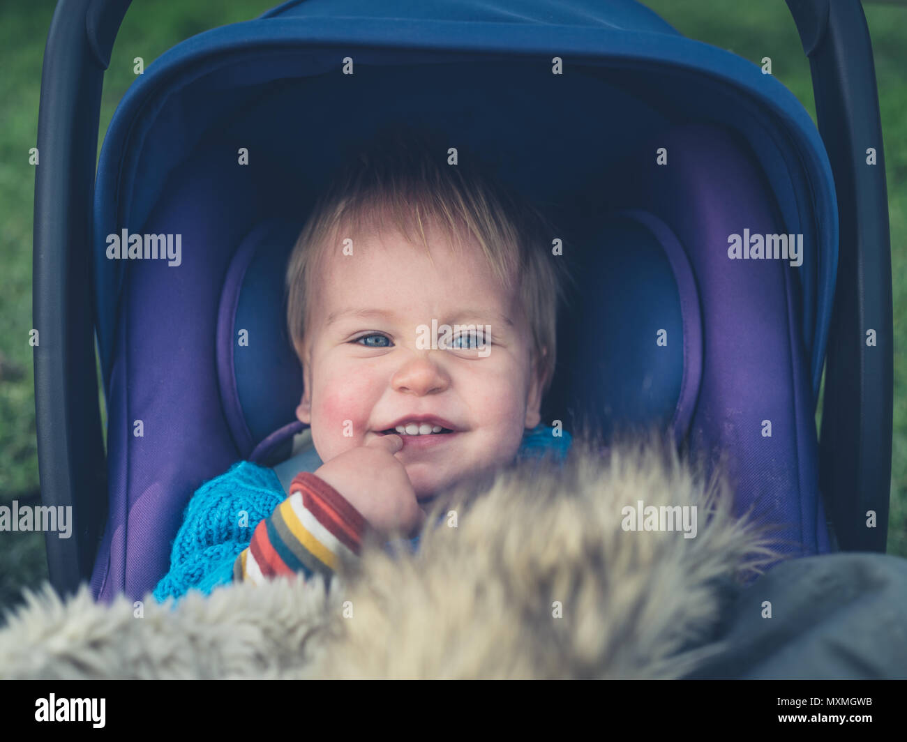 Ein süßes kleines Baby sitzt in einem Kinderwagen außerhalb Stockfoto