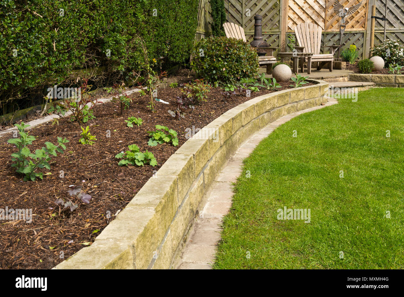 Ecke des schönen, gepflegten, privaten Garten mit zeitgenössischem Design, Pflanzen, Terrasse, Rasen & Ornamente - Yorkshire, England, UK. Stockfoto