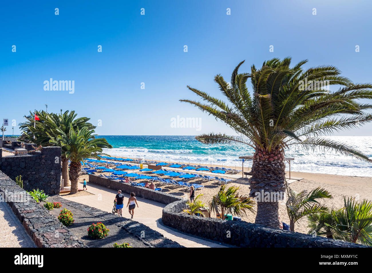 Puerto del Carmen, Spanien - 29. Dezember 2016: Tag der Blick auf die Strandpromenade mit Palmen und Strand von Puerto del Carmen, Spanien. Puerto del Carmen ist das Wichtigste zu Stockfoto