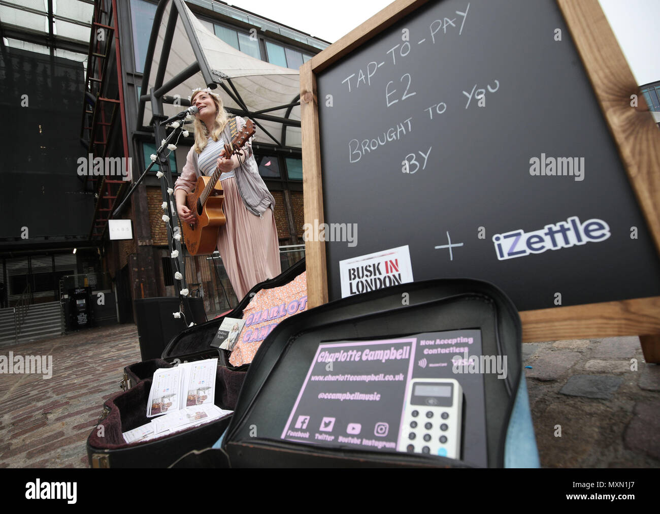 Busker Charlotte Campbell führt in Camden Market, nördlich von London, als Kate Jones, Programmdirektor bei Busk in London, schaut an. London hat erste kontaktlose Zahlung das Schema der Welt für Straßenmusikanten in Zusammenarbeit mit Technologieunternehmen iZettle gestartet. Stockfoto