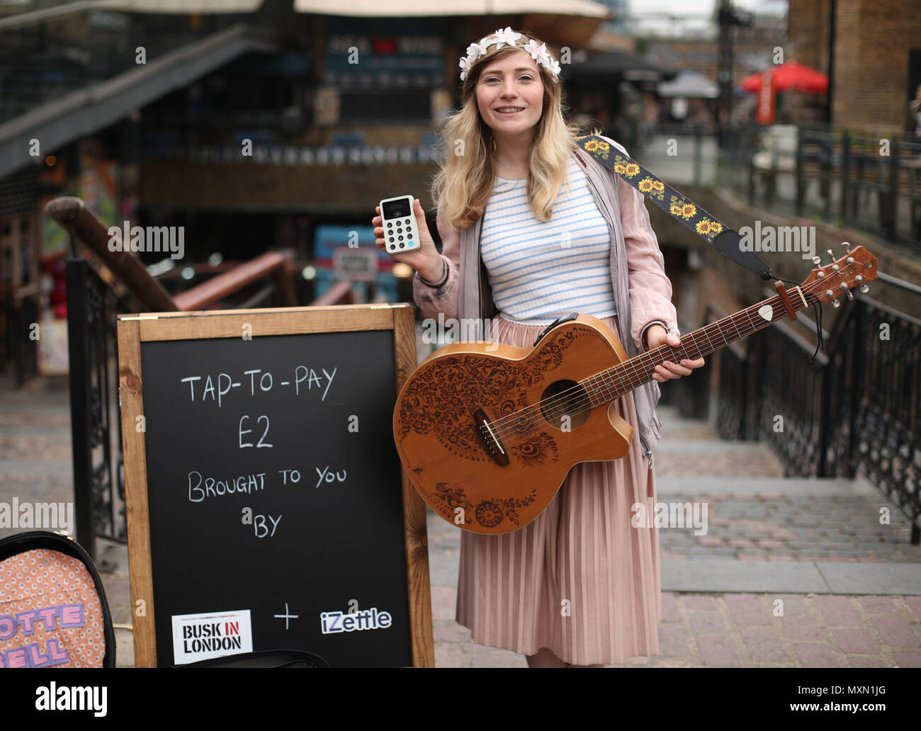 Busker Charlotte Campbell führt in Camden Market, nördlich von London, als Kate Jones, Programmdirektor bei Busk in London, schaut an. London hat erste kontaktlose Zahlung das Schema der Welt für Straßenmusikanten in Zusammenarbeit mit Technologieunternehmen iZettle gestartet. Stockfoto