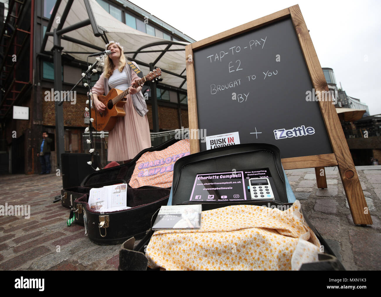 Busker Charlotte Campbell führt in Camden Market, nördlich von London, als Kate Jones, Programmdirektor bei Busk in London, schaut an. London hat erste kontaktlose Zahlung das Schema der Welt für Straßenmusikanten in Zusammenarbeit mit Technologieunternehmen iZettle gestartet. Stockfoto
