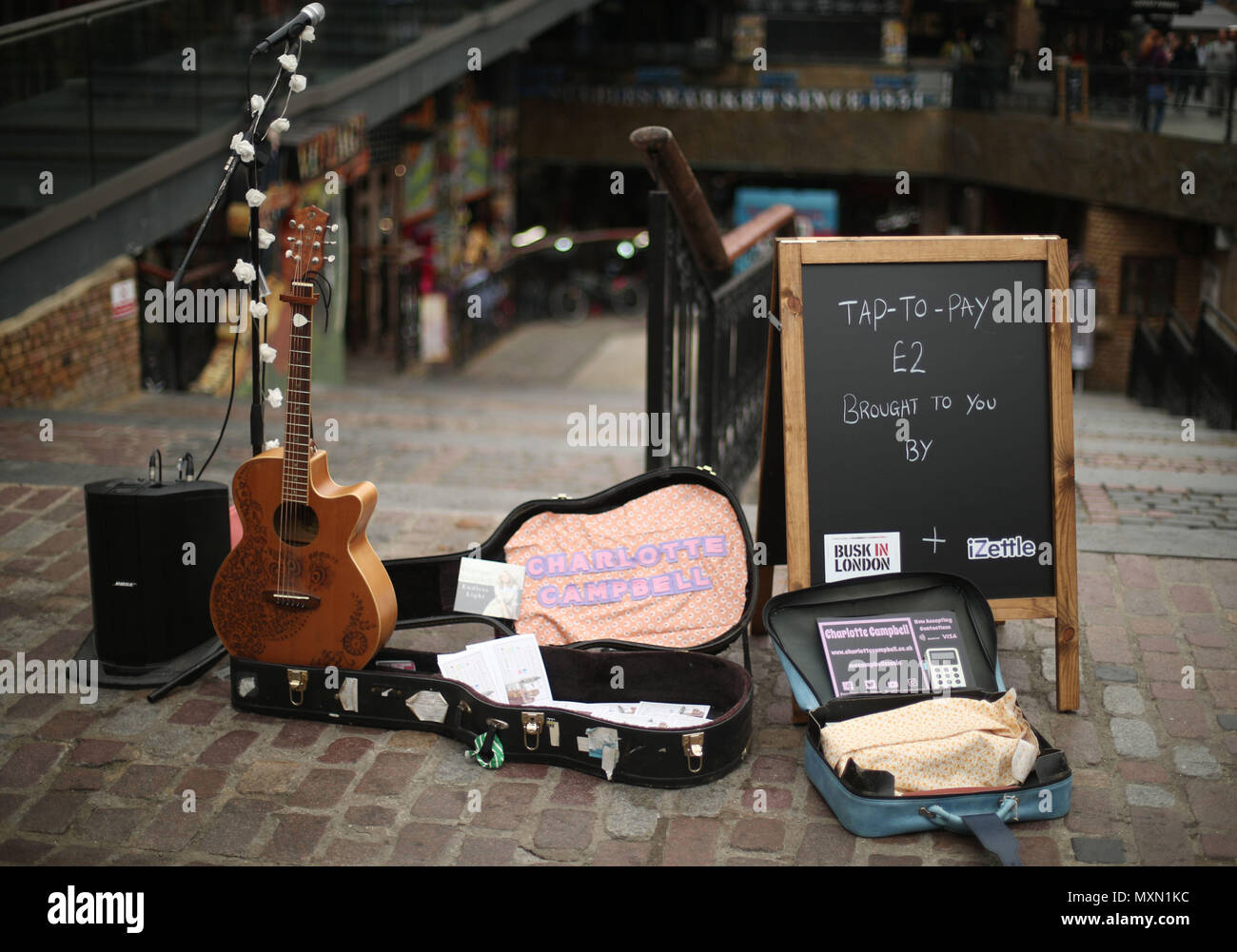 Busker Charlotte Campbell führt in Camden Market, nördlich von London, als Kate Jones, Programmdirektor bei Busk in London, schaut an. London hat erste kontaktlose Zahlung das Schema der Welt für Straßenmusikanten in Zusammenarbeit mit Technologieunternehmen iZettle gestartet. Stockfoto
