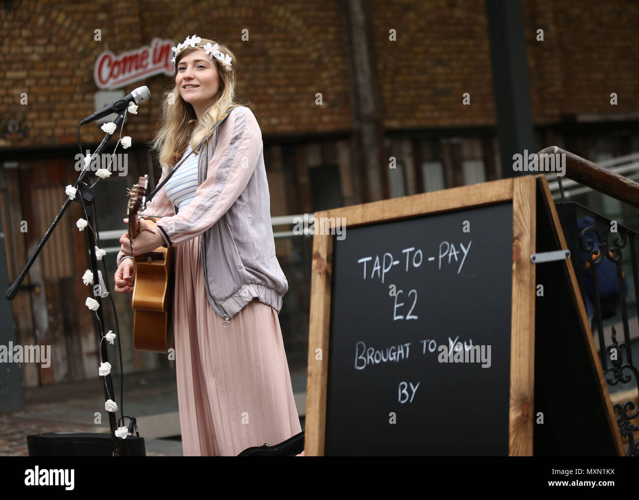 Busker Charlotte Campbell führt in Camden Market, nördlich von London, als Kate Jones, Programmdirektor bei Busk in London, schaut an. London hat erste kontaktlose Zahlung das Schema der Welt für Straßenmusikanten in Zusammenarbeit mit Technologieunternehmen iZettle gestartet. Stockfoto