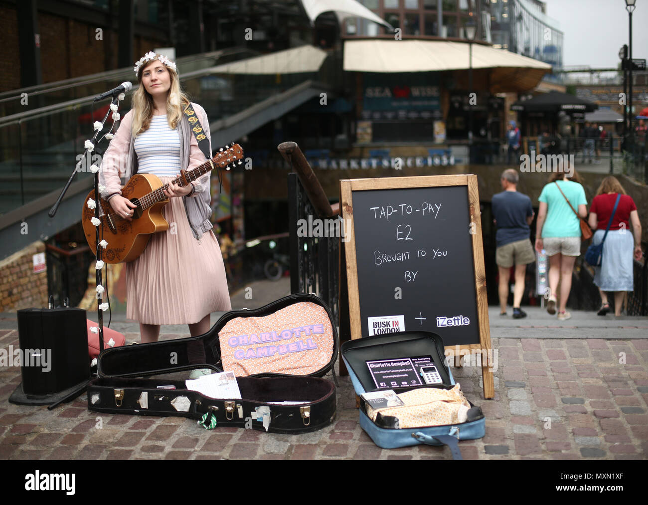 Busker Charlotte Campbell führt in Camden Market, nördlich von London, als Kate Jones, Programmdirektor bei Busk in London, schaut an. London hat erste kontaktlose Zahlung das Schema der Welt für Straßenmusikanten in Zusammenarbeit mit Technologieunternehmen iZettle gestartet. Stockfoto