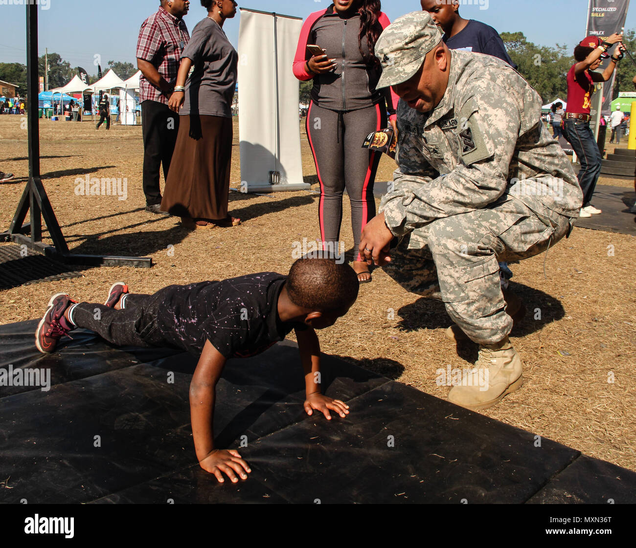 Armee Sgt. Marcus T. Williams, chemische Spezialist, 143d Sustainment Command (Auslandseinsätze), ruft ein Junge eine weitere Wiederholung während pushup Herausforderung durchgeführt 19.11.2016, an der GoArmy.com interaktive sowohl auf dem Messegelände liegt ausserhalb des Lagers Welt Stadion in Orlando, Fla. Williams, ein Eingeborener von Orlando, Eintritt in den aktiven Dienst und Soldaten, sich Zehntausende Fans an der Florida Klassiker, einer der größten Fußball-rivalitäten der Nation zwischen zwei historisch schwarze Hochschulen. Die Truppen verwaltet mehrere interaktive Herausforderungen, die Stärke der Lüfter getestet Stockfoto