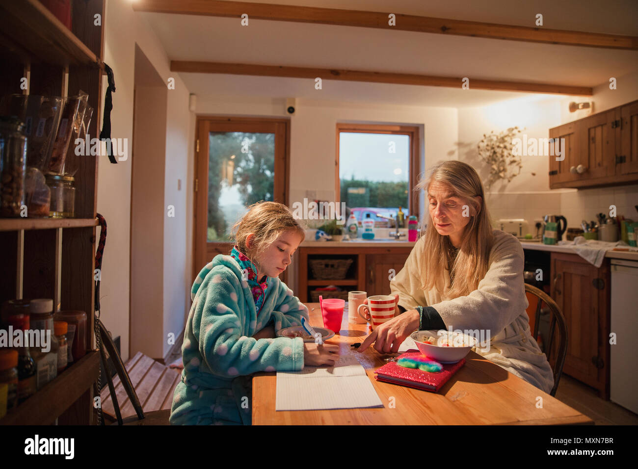 Mutter und Tochter am Tisch am Morgen sitzen. Mutter hilft, ihre Tochter mit ihren Hausaufgaben vor der Schule. Stockfoto