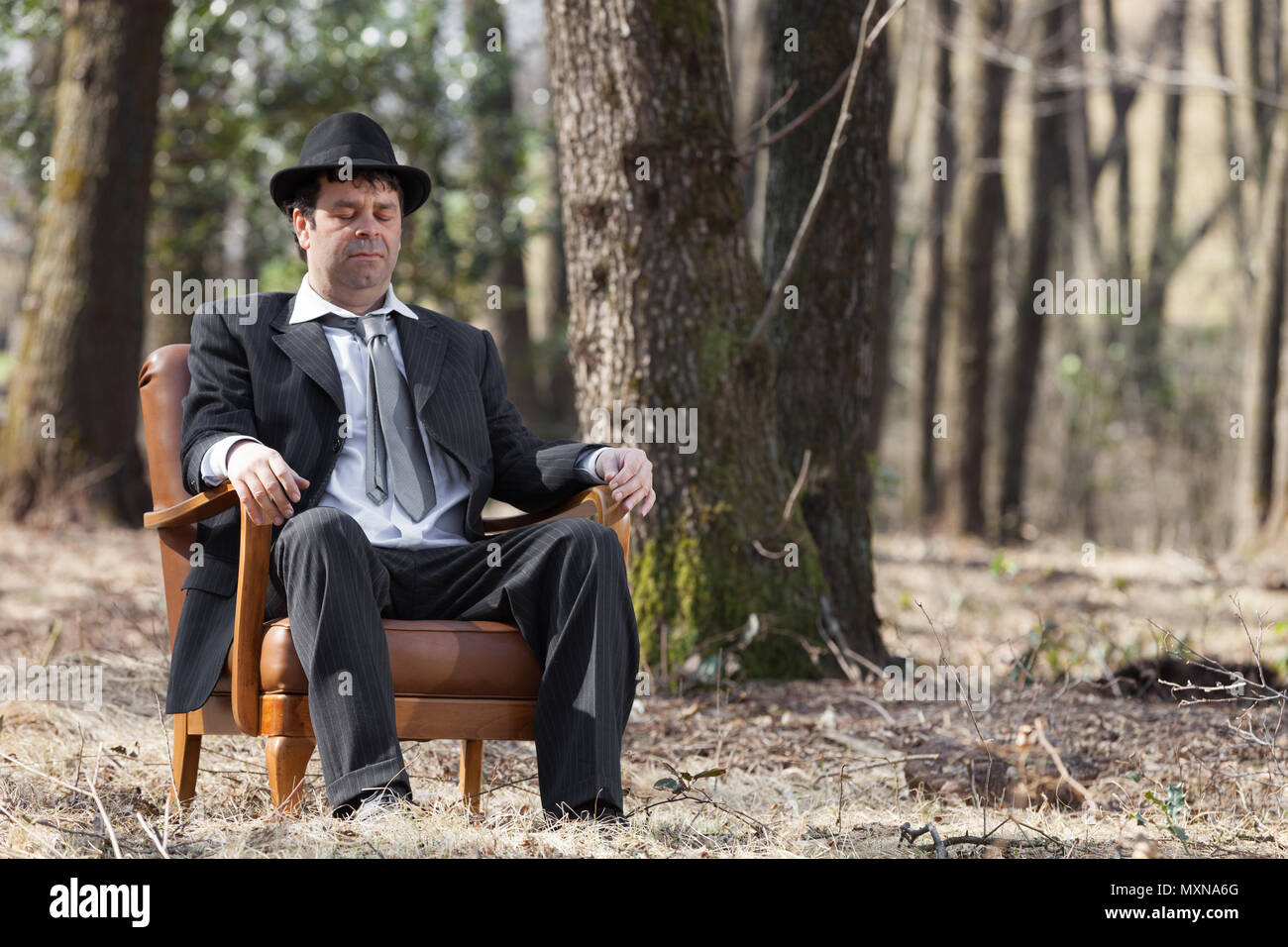 Mann allein im Wald sitzt auf einem Sessel Stockfoto