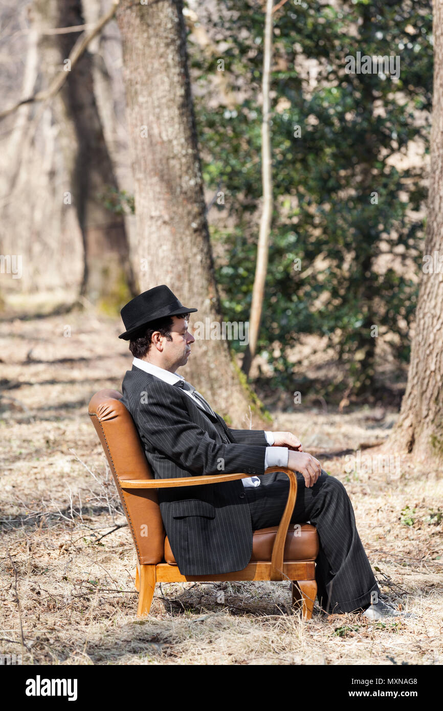 Mann allein im Wald sitzt auf einem Sessel, Seitenansicht Stockfoto