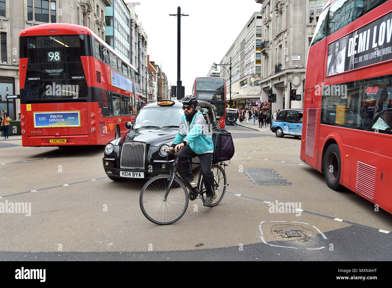 Eine Deliveroo Lieferung Reiter auf seinem Fahrrad das Oxford Circus Road Kreuzung verhandelt in Central London. Stockfoto