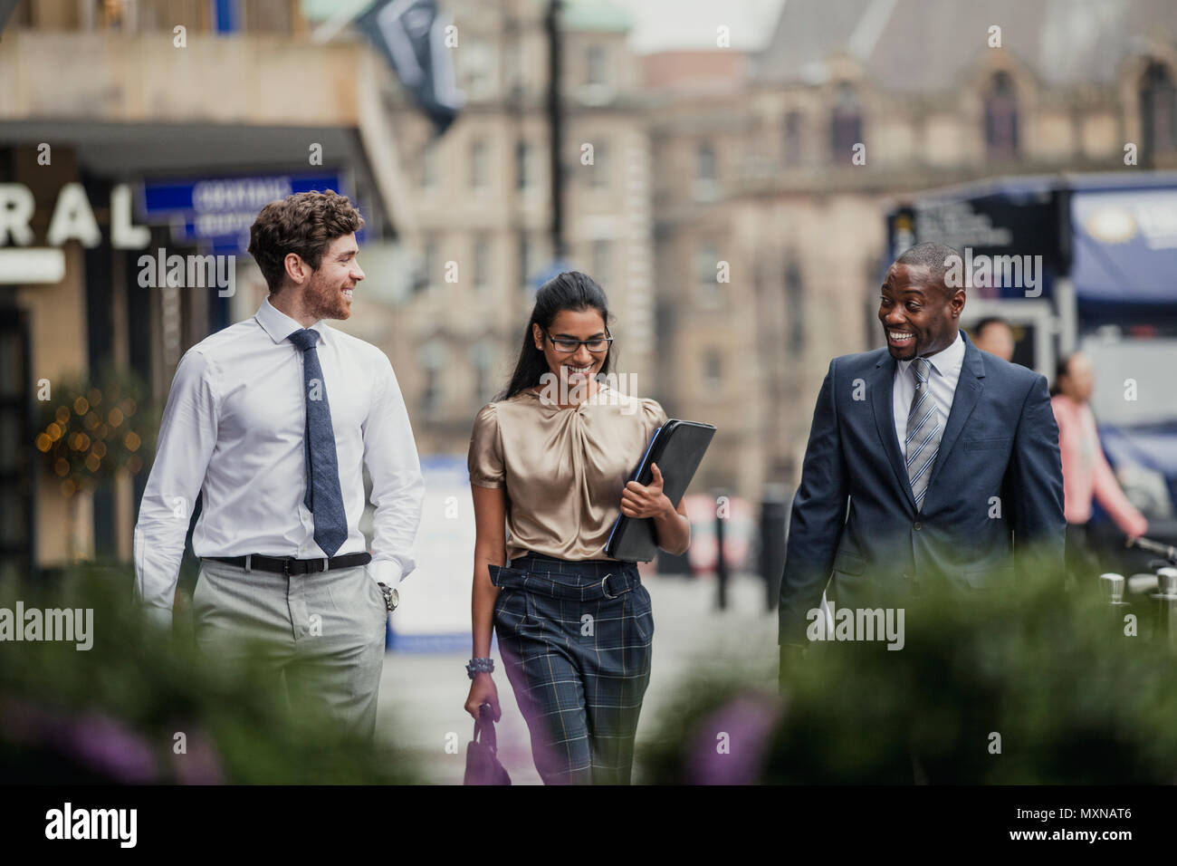Vorderansicht von drei Geschäftsleute zu Fuß durch die Straßen der Stadt. Alle drei Personen sind formelle Kleidung tragen. Stockfoto