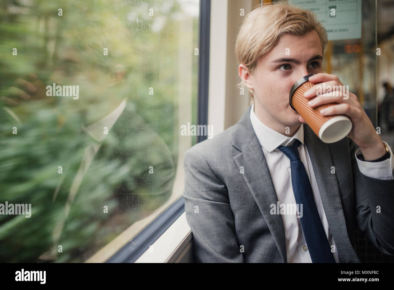 Jungen trinken Geschäftsmann Kaffee auf seinem morgendlichen Weg zur Arbeit. Mit der Bahn als Verkehrsträger. Stockfoto