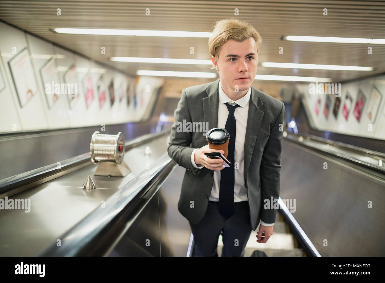 Junge Unternehmer, sich eine Rolltreppe auf seinen Morgen pendeln zur Arbeit. Stockfoto