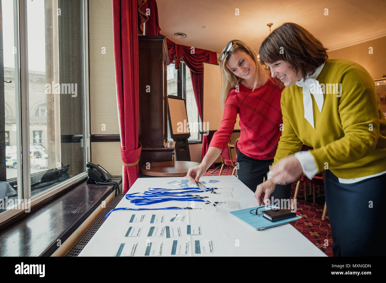 Zwei Unternehmerinnen auf der Suche nach Namensschilder auf dem Tisch, bevor die Konferenz beginnt. Stockfoto