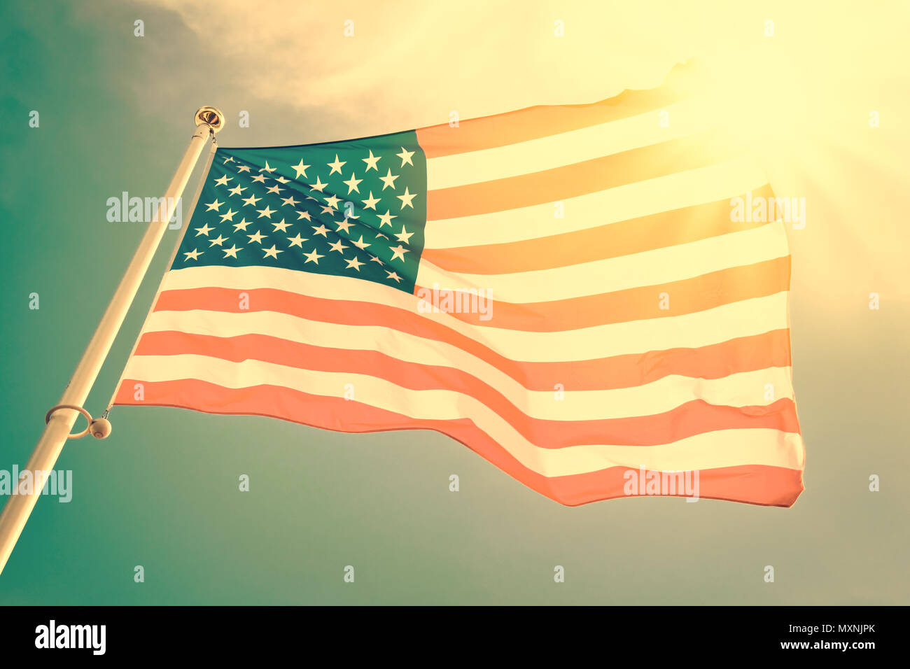 Amerikanische Flagge auf einer Stange in den Wind, Sonne und blauer Himmel, vintage Prozess Stockfoto