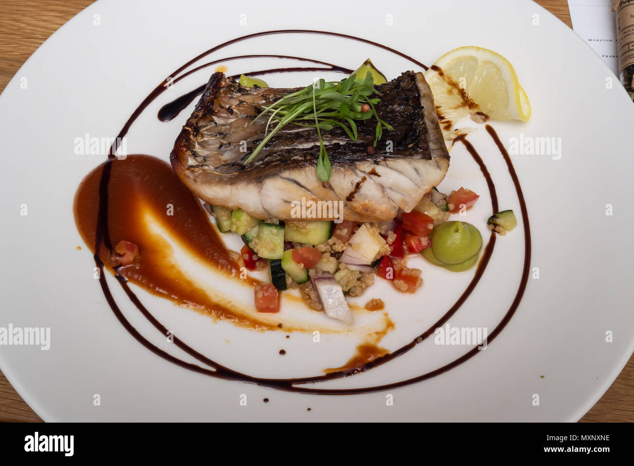 Fine Food: Gegrillter baramundi auf einem Bett von frischen Tomaten, Gurken und Quinoa Stockfoto