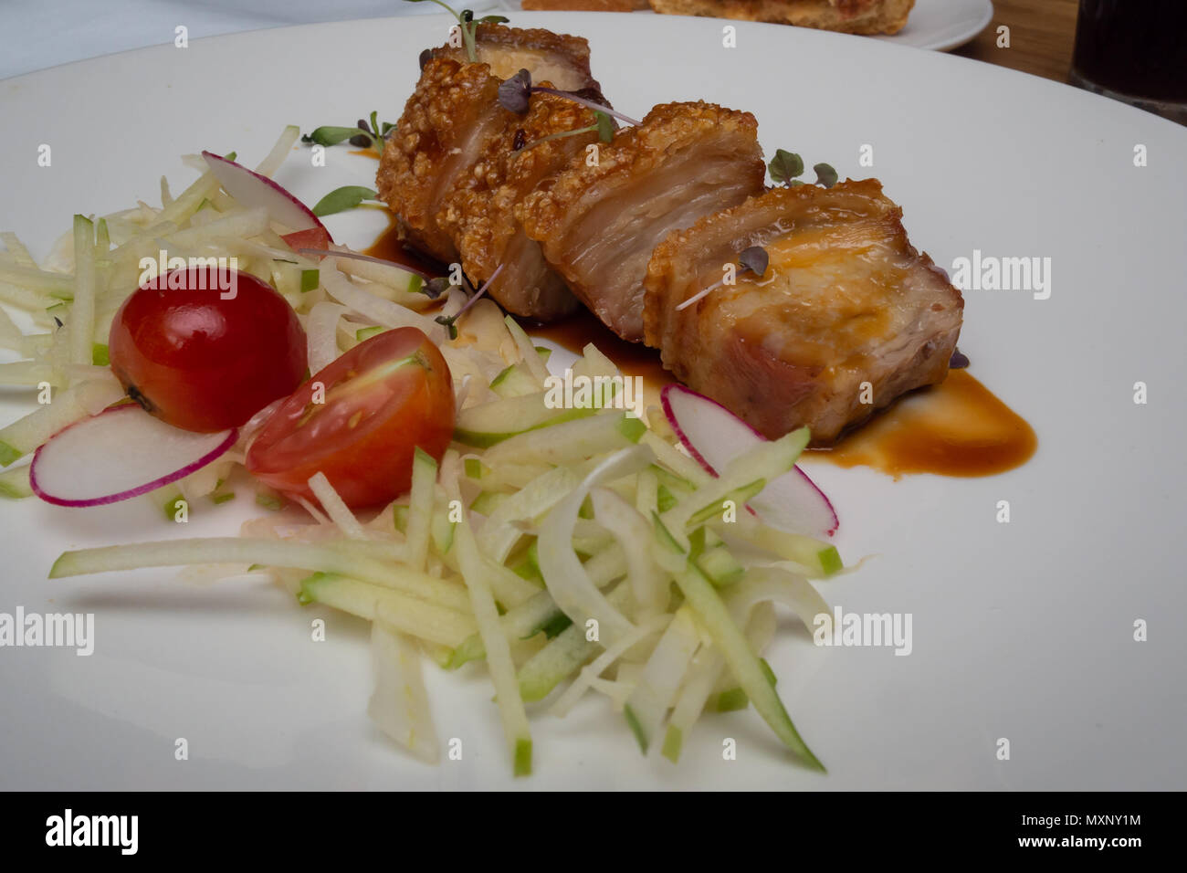 Fine Food: knuspriger Schweinebraten mit einem Apple salat Cherry Tomaten und roten Rettich Stockfoto