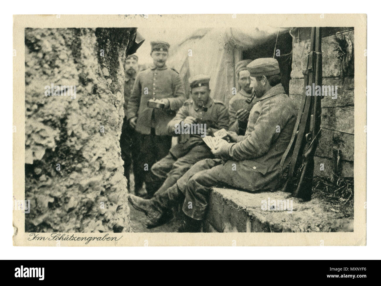 Deutsches Historisches Foto Postkarte: Soldaten im Schützengraben Tabakpfeifen, Karten spielen. Hält man eine Pfanne mit Essen. Im ersten Weltkrieg zwischen Angriffen. Stockfoto