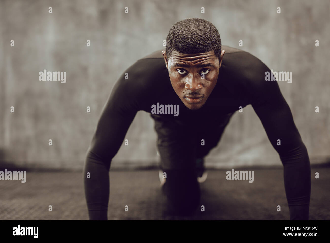 Athletischer Mann tun Push up im Fitnessraum trainieren. Muskulöse Mann in engen schwarzen Outfit tun crossfit Training. Stockfoto