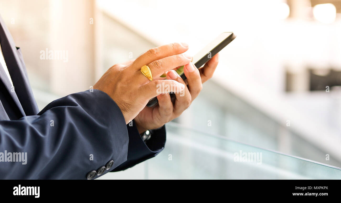 Asiatische Geschäftsmann mit Mobiltelefon für Decke und Textnachrichten auf Ihr Mobiltelefon Stockfoto